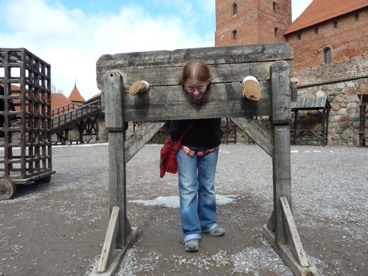 Me in the stocks at Trakai Castle, wearing jeans and the sheepskin mittens I bought three years earlier for my Finland trip.