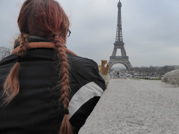 A picture of the back of my head as I sit on the steps at the Trocadero looking across at the Eiffel Tower. It's a grey winter day and my hair is streaked with badly-dyed reddish dye.