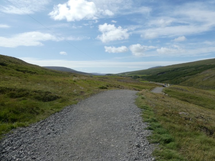 A gravel path gently winding its way through undulating green hills, almost as far as the eye can see.