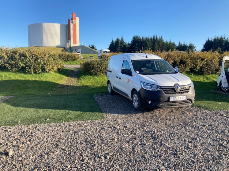 My campervan parked in a space at Hofn campsite, a small white van in the sun.