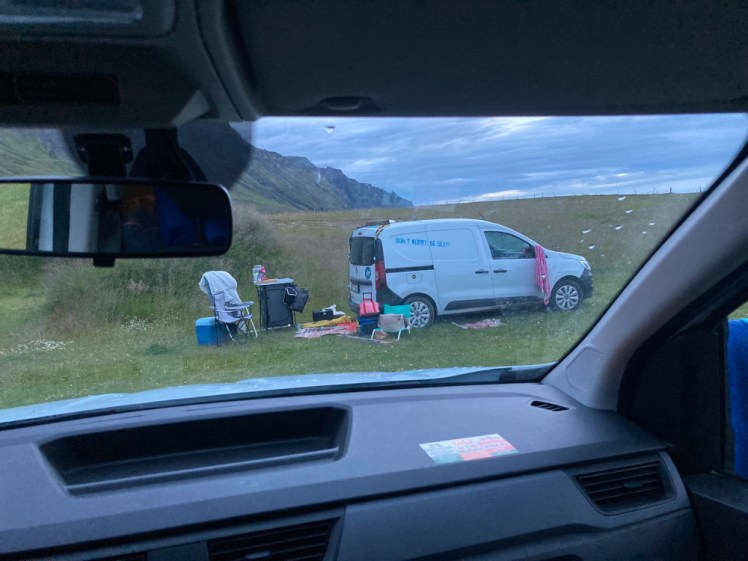A view around 11pm out the front of my van, of another van with more stuff piled on and outside it than you'd think possible to fit in there, especially when there are two people sleeping in there too.