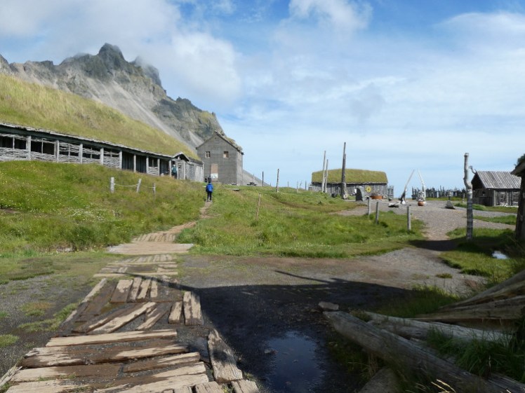 The Viking village as seen from the far side. The mountain looms over it all and most of the buildings have turf roofs.