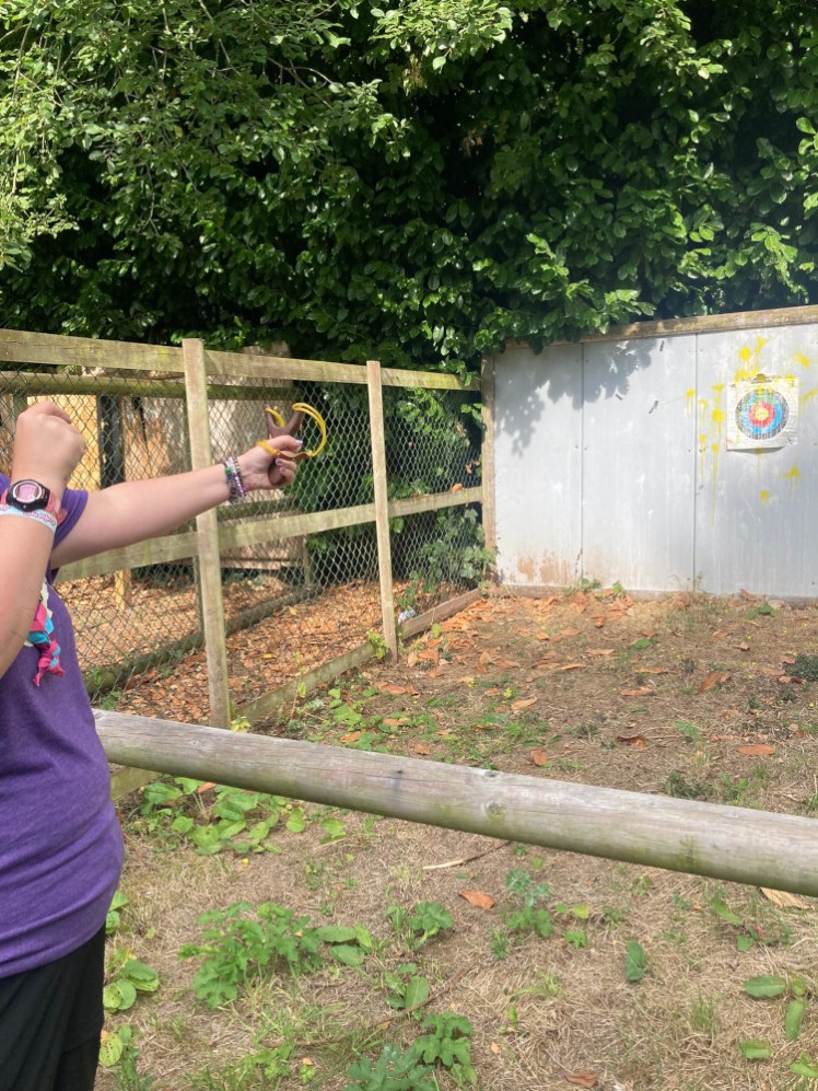 A sliver of me pulling back a catapult. My photographer has captured the target, splattered with yellow paint from where various people have hit with the paintball from their catapult.