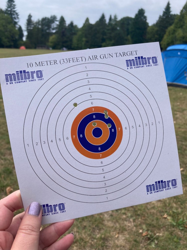 A square paper target held up at the campsite afterwards, with four holes in the 7-9 zone and one just breaking the line between 5 and 6.