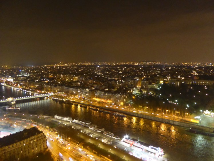 The view of city lights from the Eiffel Tower. The orange lights across the city give a kind of brown glow to the sky.