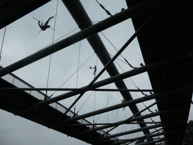 Father Bernatek Bridge, a footbridge with acrobatic statues in various poses in the wires holding up the curved support beam.