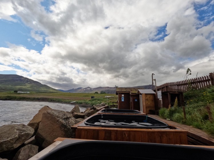 A row of hot tubs in wooden surrounds, right on the seashore. A few sheds function as showers and changing rooms.