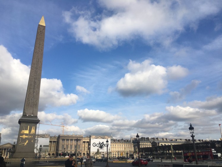 Place de la Concorde, with the Luxor Obelisk in the foreground, its gold tip and lettering reflecting in the sun.