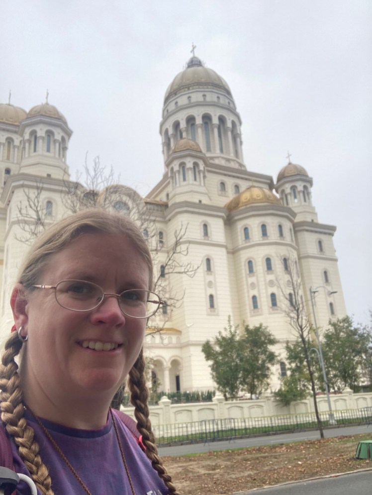 Me in a purple t-shirt outside the National Cathedral during its inauguration ceremony. The cathedral is very overexposed but you can still see that it's big and gold.