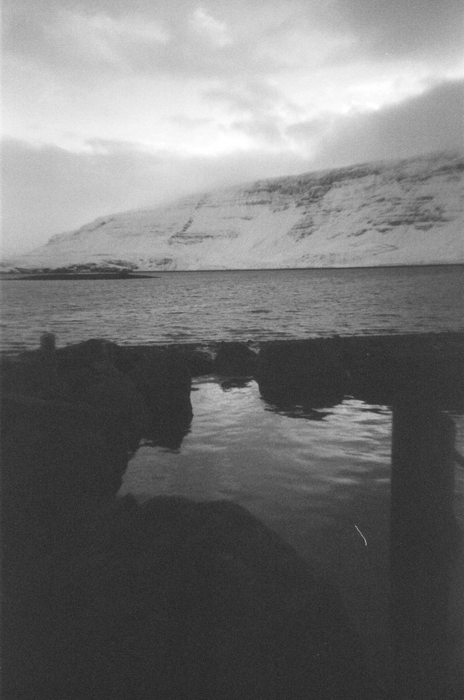 One of Hvammsvik's hot pools with the fjord and the steep mountains behind it.