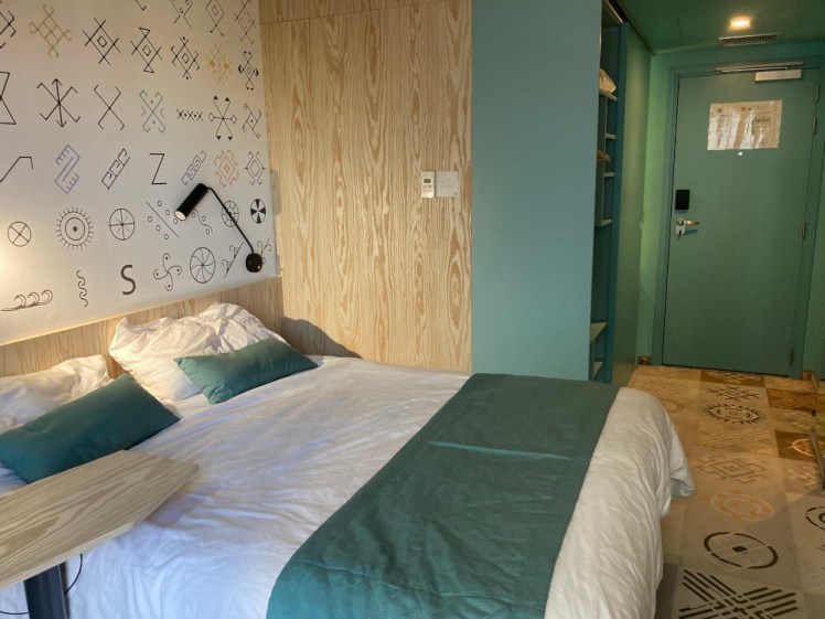 My room in the Ibis Styles, which is themed in a sort of teal-green, with a cover over the foot of the bed, the back of the door and the cupboard unit all in teal. The back wall is decorated in stitches from traditional Romanian embroidery.