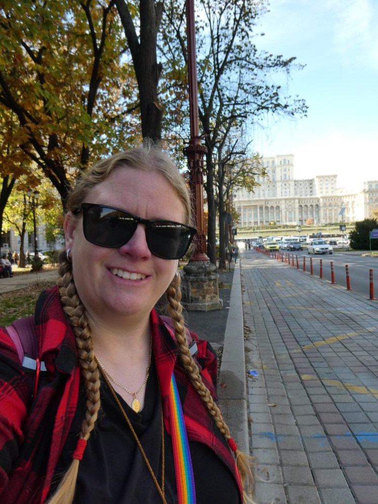 A selfie, this time with a red checked shirt over my t-shirt, in front of Bucharest's Palace of Parliament, which is huge enough that it doesn't really matter that I'm halfway down the road leading away from it.
