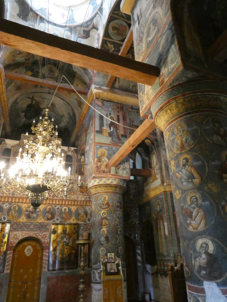 Inside Snagov Monastery, covered floor to ceiling in murals in prominent blues and golds, plus an elaborate chandelier.