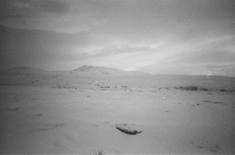 A view of a small mountain beyond a field of snow.