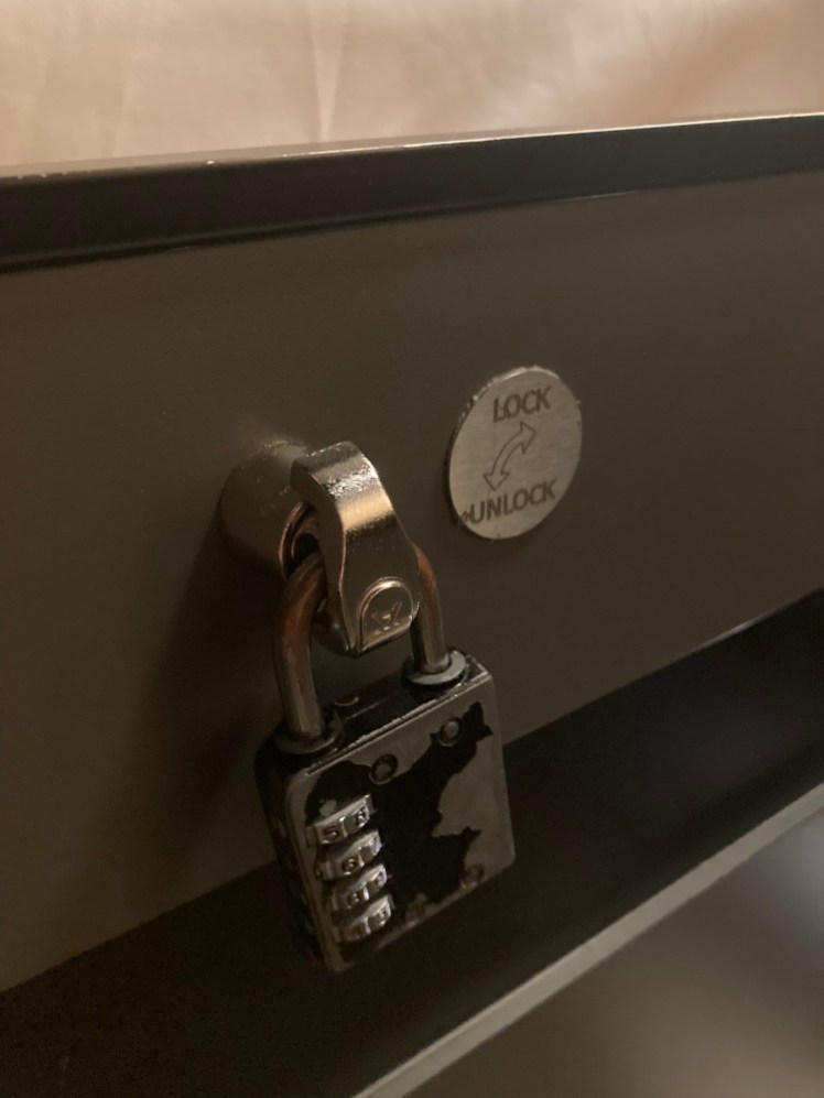 A battered padlock hanging from a lock mechanism on the outside of the capsule.