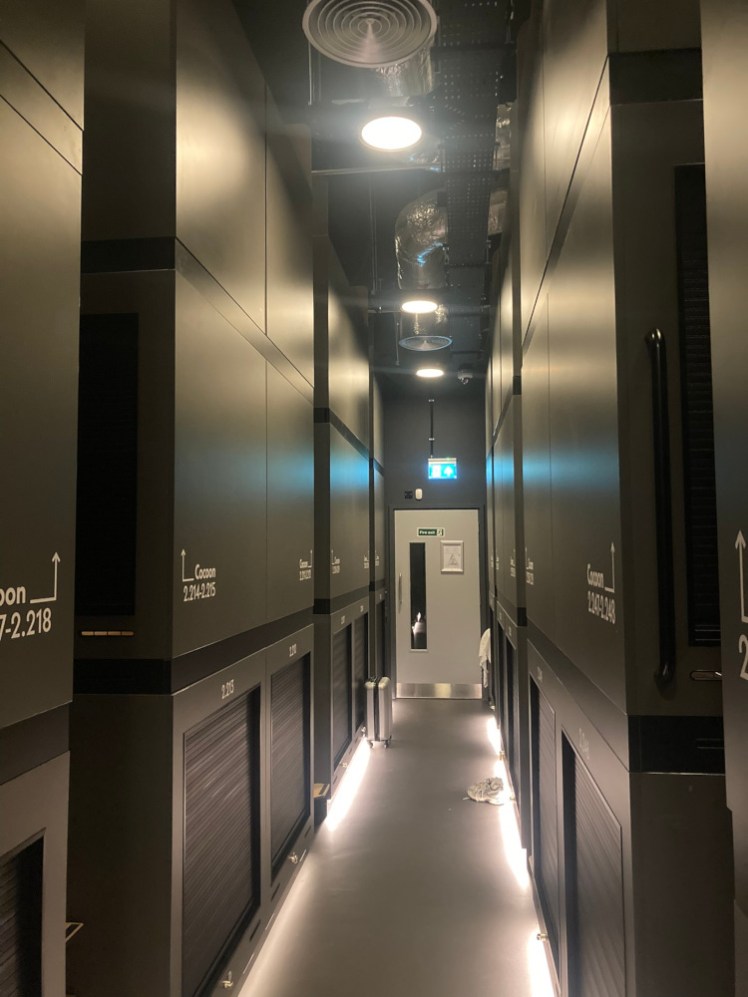 My dormitory, a narrow corridor with three storeys of capsules on each side, in pairs with a set of steps in between.