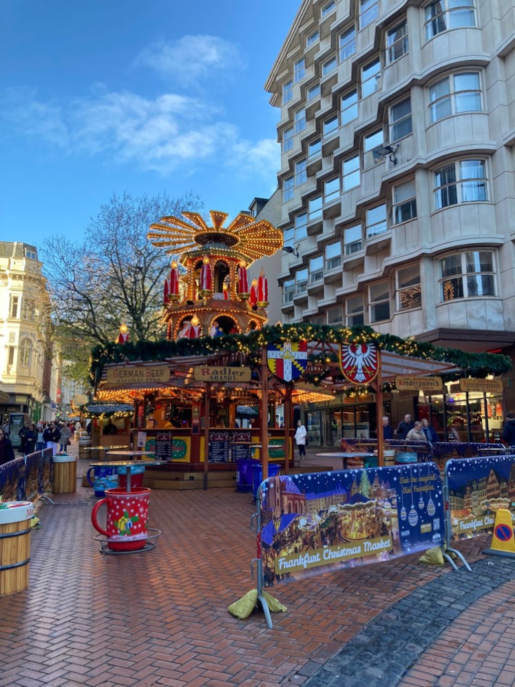 A drinks stall with an elaborate carousel thing on top, surrounded by candles at least six feet tall. Underneath are wooden signs for all the drinks available and a very prominent table in the shape of a big red mug.