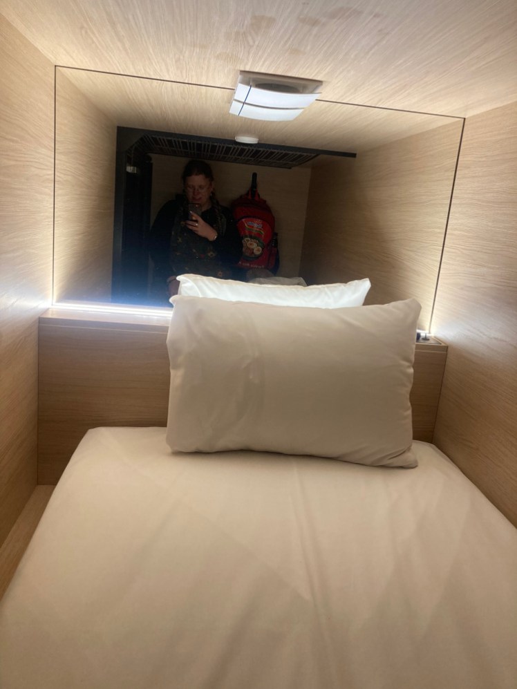 Me crouched in the entrance to the capsule, reflected in the mirror at the pillow end. The way I'm crouched makes it look quite cramped.