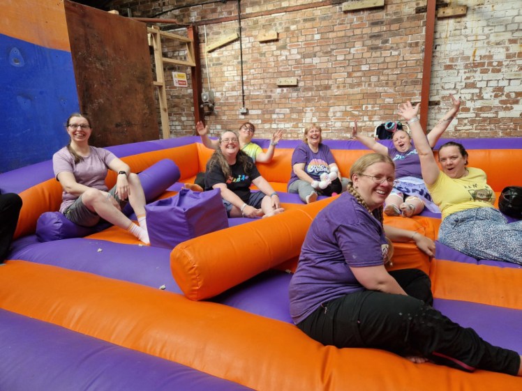 Nelson Patrol, mostly wearing Patrol purple, sitting on the purple and orange inflatable gladiator arena.