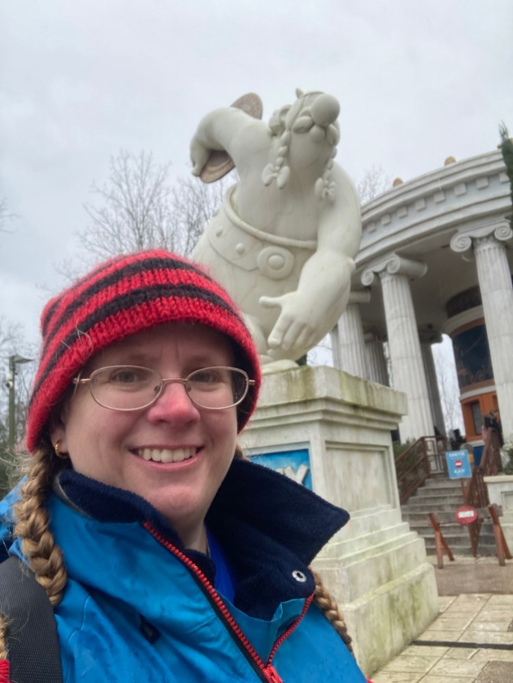 A selfie with a marble statue of Obelix preparing to throw a discus.