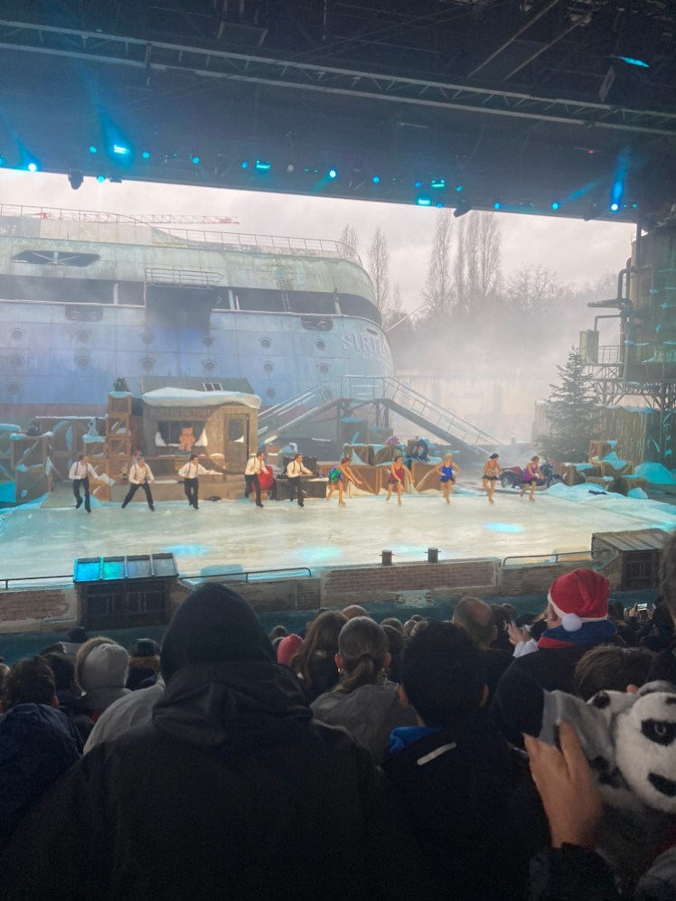 The finale of Qui veut la peau du Père Noël? as seen from halfway up the seating. The scene is the back of a factory, with boxes and offices and a rusty ship as background and it all got used.