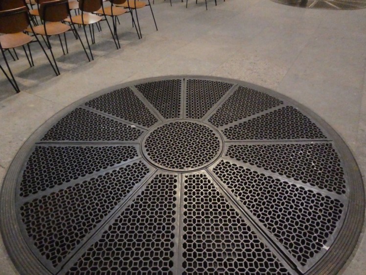 A massive circular air vent in the floor, shaped a bit like a rose window. You would not believe how much hot air this thing is putting out.