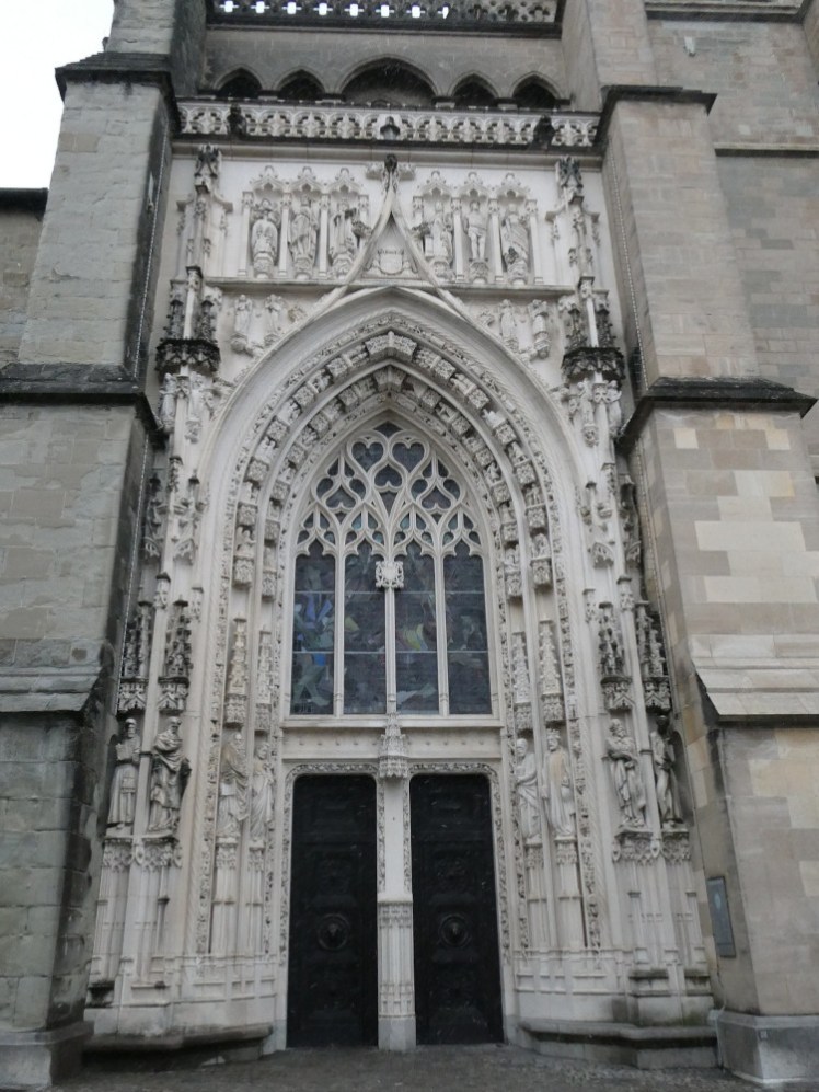 The elaborate west door of the cathedral, which has stained glass and a lot of decoration. It's also noticeably whiter and cleaner than the rest of the front.