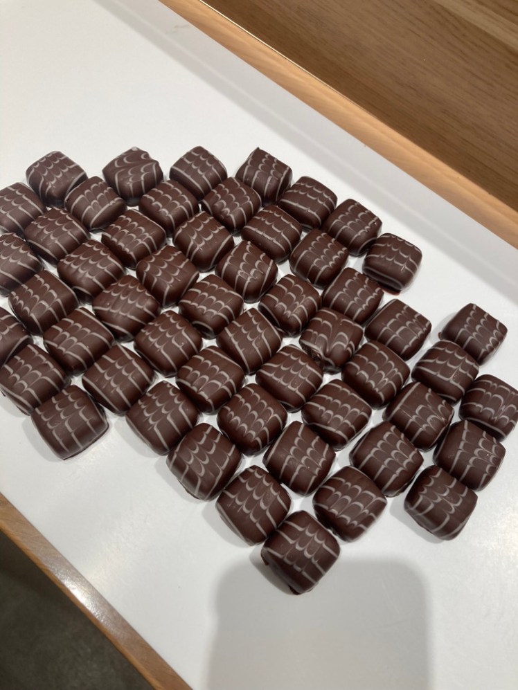 A tray of lemon chocolates, which are little squares with thin wiggly piped white chocolate lines on top.