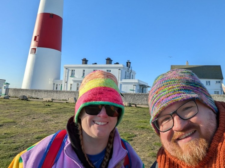 Me and Tom, in our Tom-made knitted hats and our rainbow tops with a lighthouse behind us.