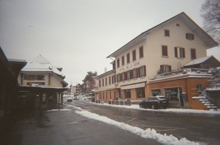The station hotel and snowy melted road outside Palezieux station.