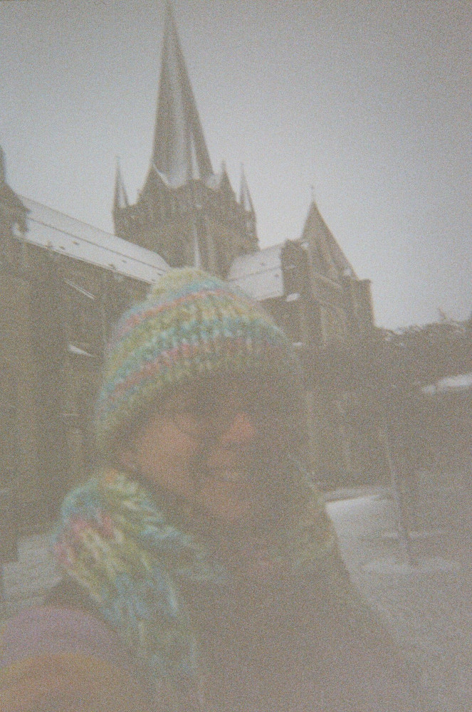 A selfie outside the cathedral during the snowstorm. You can make out the snow on the cathedral roof but otherwise, the picture is a lot browner and grainier than I'd like, although you can see the pastel shades of my stripy hat & scarf quite well.