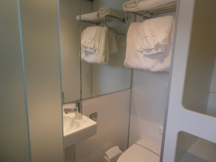 The bathroom door slid open, showing a hint of toilet, the tiny sink and the towels on the rack on the wall.
