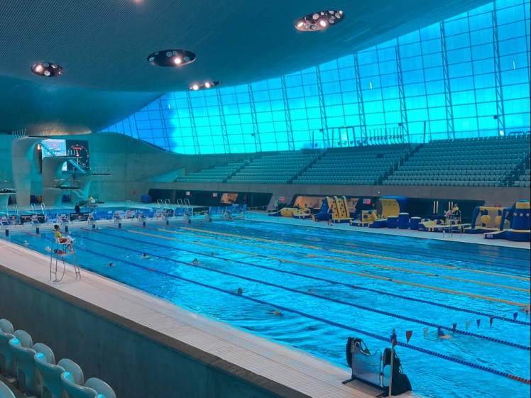 The competition pool in the main hall. The whole room is illuminated in blue from the massive blue windows along the top of both sides and there are banks of seats along the side.