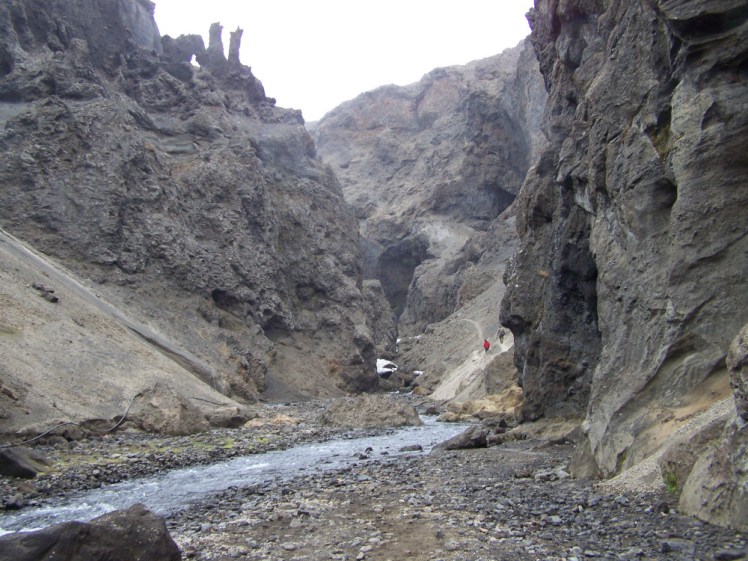 A canyon carved out of yellow-grey stone, with twisted shapes that vaguely resemble a dragon crowning the crumbly walls. It's bigger than it looks - there are some people in colourful waterproofs walking up a slope, about a fifth of the size they look like they should be.