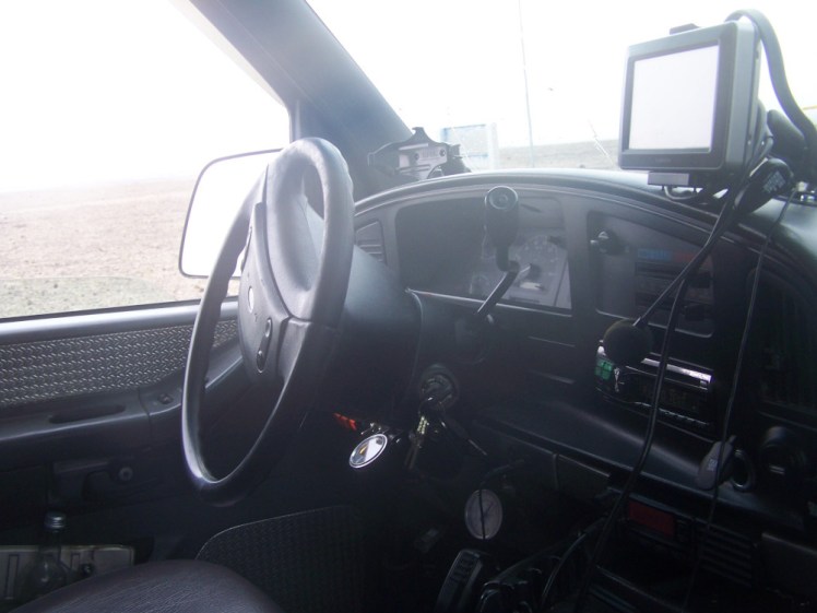 Inside the jeep. My camera is misted up and full of mud, so the picture is misty. There are a lot of wires sticking out of the dashboard, including a chunky satnav and a tour guide headset.