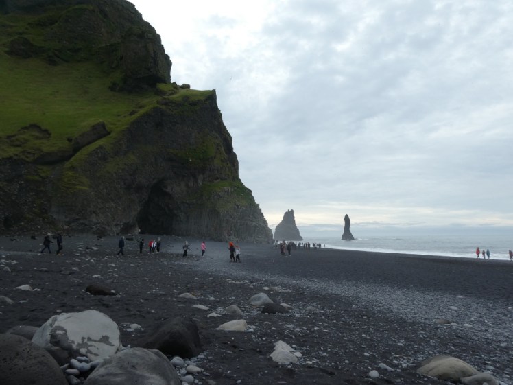 Reynisfjara with its famous cliff, cave and pinnacles all showing in a picture from a bit further back. The moss on the cliff is quite bright green, so for once it actually looks like it's summer here.