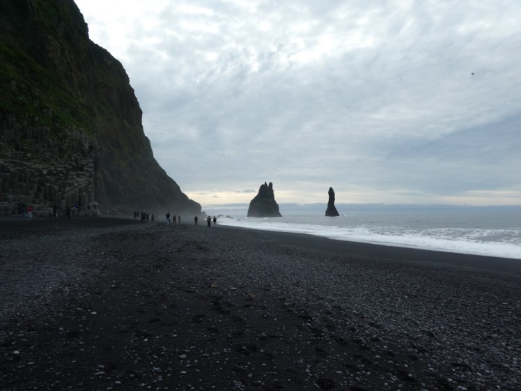 Looking down Reynisfjara towards the cliff and the pinnacles on a grey summer day with a bit of mist low on the beach, almost like a curtain of magic starting to sweep in.