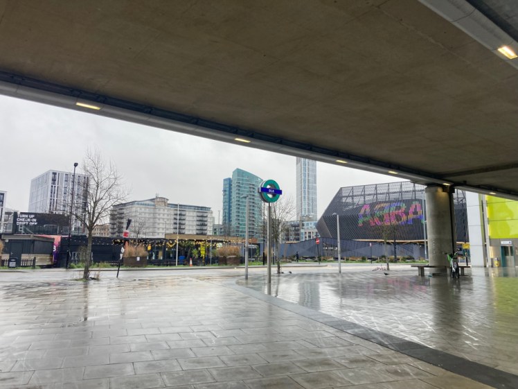 Snoozebox, on the left, and Abba Arena, on the right, as seen from underneath Pudding Mill Lane DLR station. The hotel is a stack of black-painted shipping containers, looking surprisingly subtle, whereas the Abba Arena is a kind of 3D diamond with ABBA on the front pulsing in a rainbow of colours.