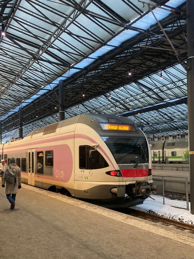 A single decker train, white with faded red markings and a bright orange display on the front declaring it "Stängd" and "Close". If you look closely, it also says this on the information panels by the doors.