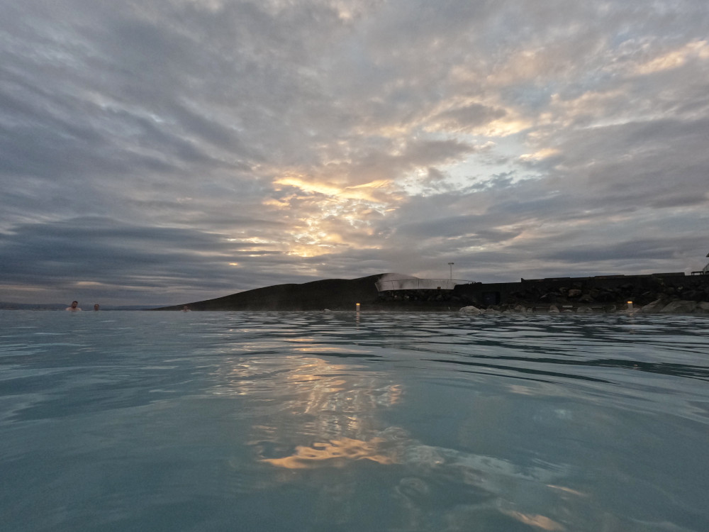The sun setting over the mountain opposite the Earth Lagoon, turning the many clouds yellow.