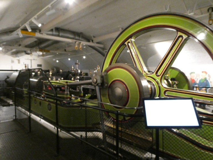 The shiny green and brass engines in the engine room.