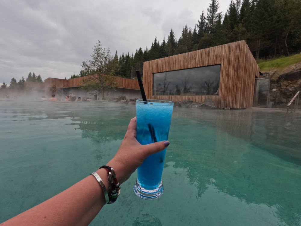 The Forest Lagoon's signature non-alcoholic cocktail in a branded cup on a background of the lagoon.