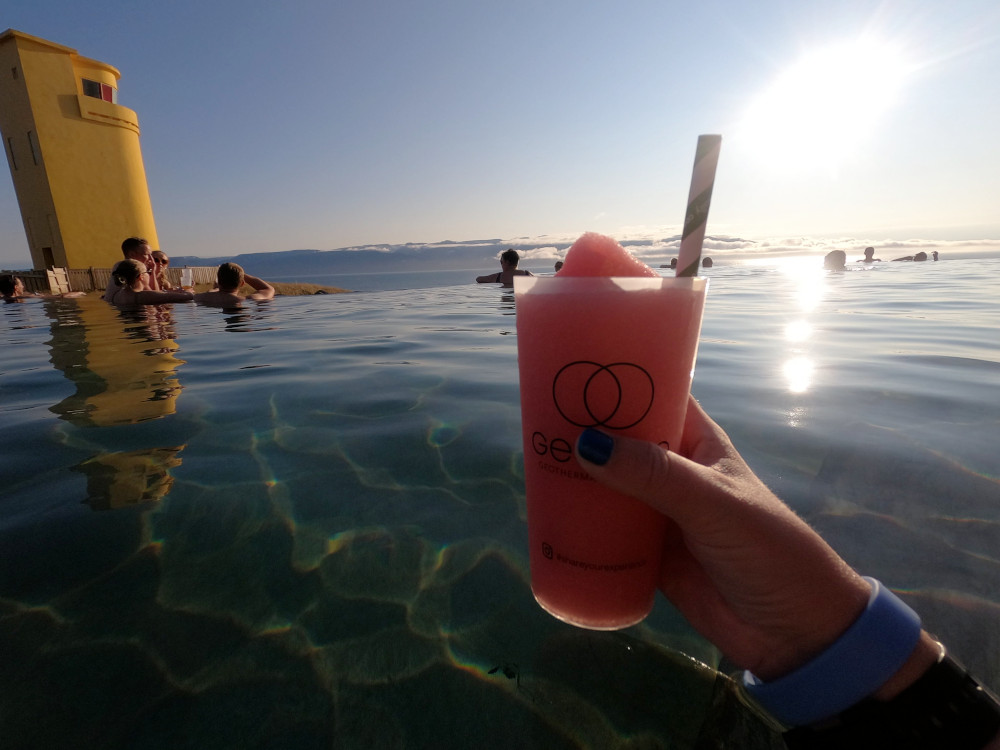 A bright pink slushie in a branded cup in the main pool with the lighthouse in the background.