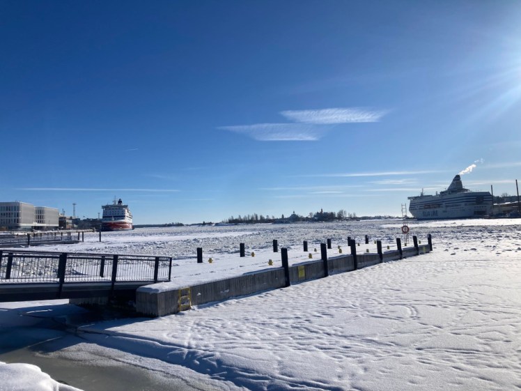 Helsinki's harbour, completely frozen and covered in snow, looking perfectly clean and white under a blue sky.