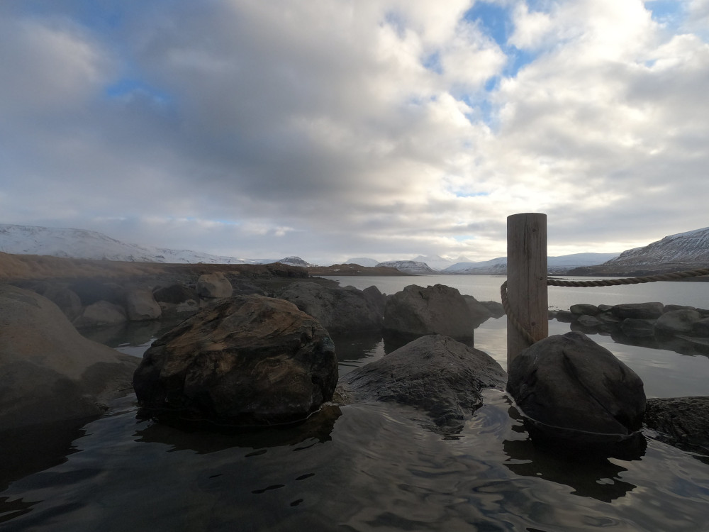 One of the pools in winter, ringed by black rocks.