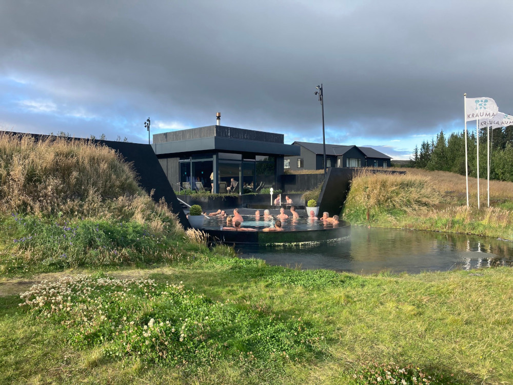 Krauma as seen from the path up from the car park, where the front pool pokes out from behind turf walls, giving you a glimpse inside from outside and of the hot spring from the inside.