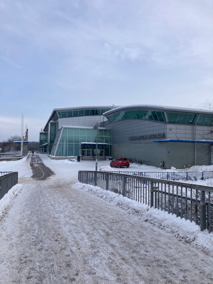 Mäkelänrinne from the other side of the road, in the snow. It's a pretty uninspiring grey building but you can see the inclined glass walls - here enclosing reception but round the back, it shows off the pool.