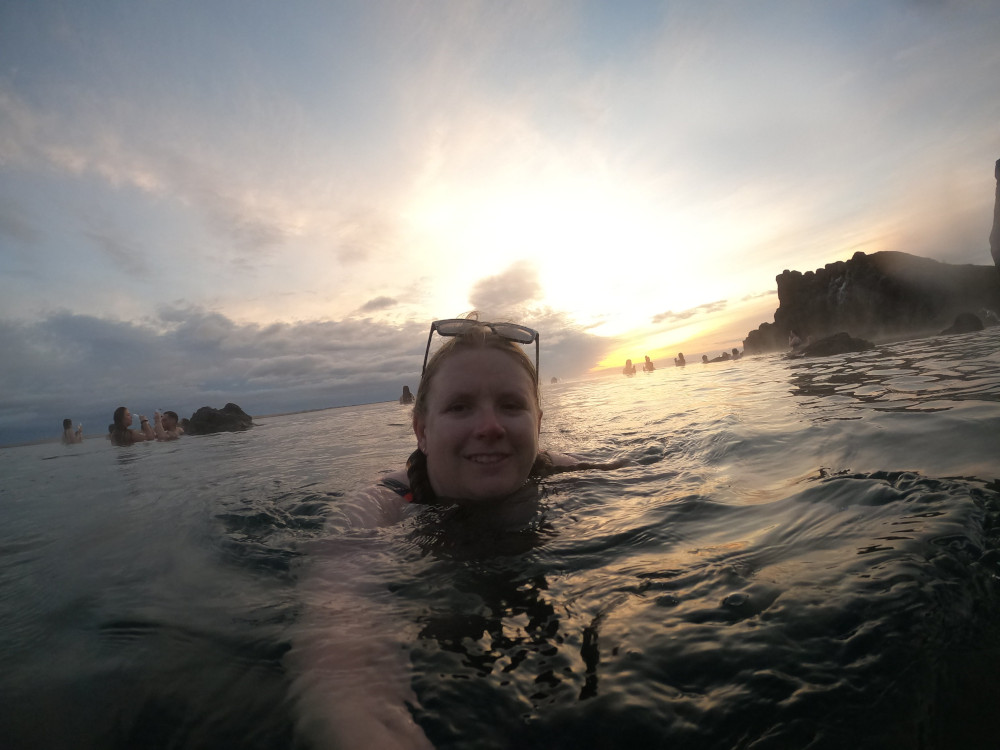 A selfie in the pool with the sunset and the cliff behind me.