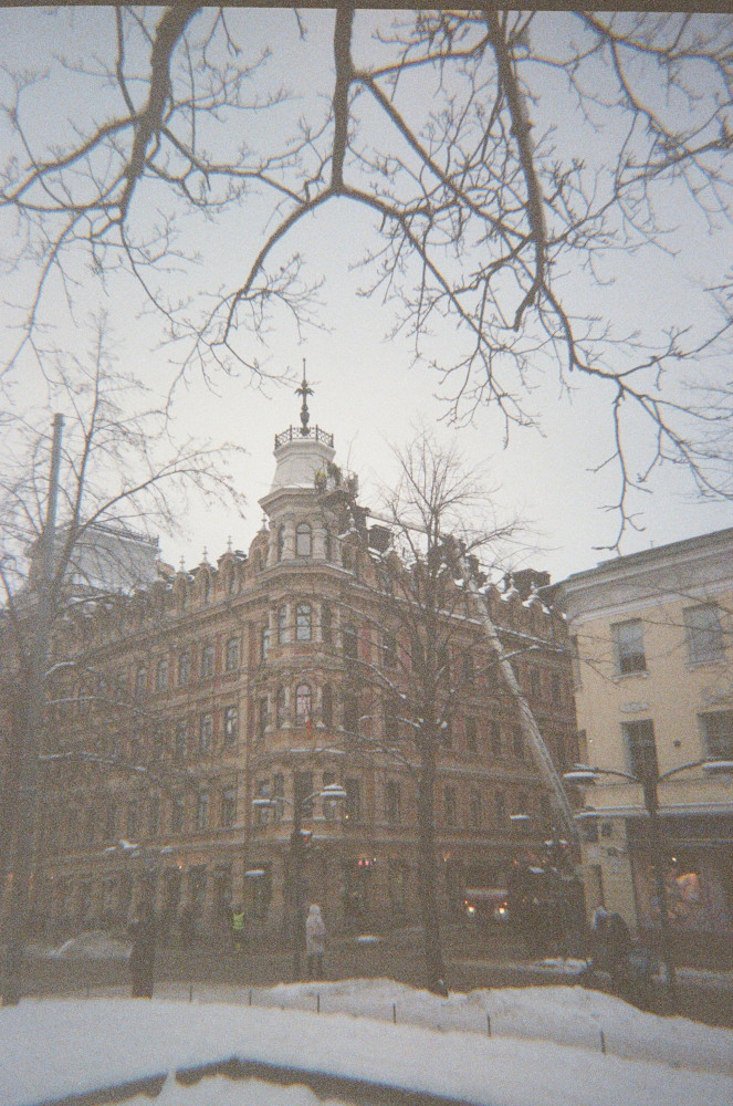 A building in Helsinki being cleared of snow on a snowy day.