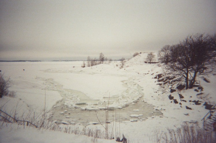 The frozen sea looking a bit yellow and choppy and fragile near the coast.